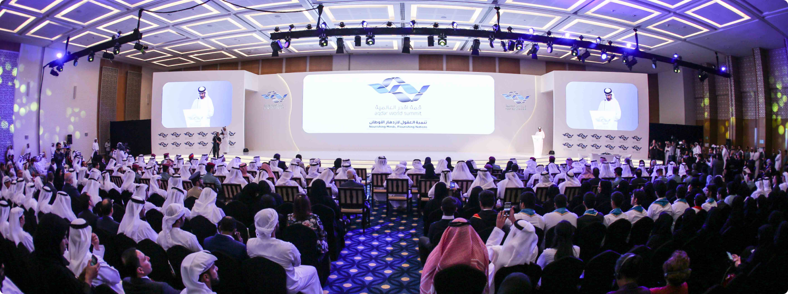 Conference hall with staged seating and large presentation screens