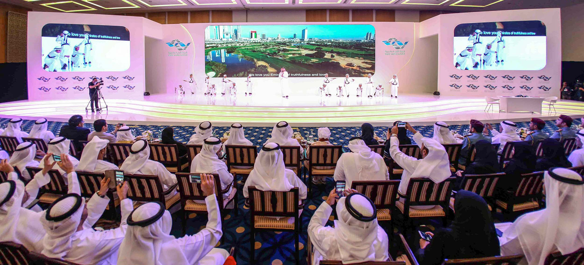 Large conference stage with LED screens and seated audience in Dubai